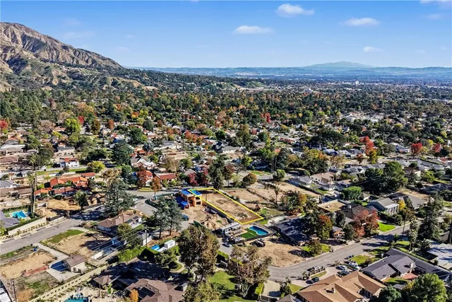 an aerial view of residential house with green space and mountain view in back