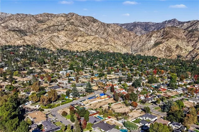 an aerial view of residential house with green space and mountain view in back