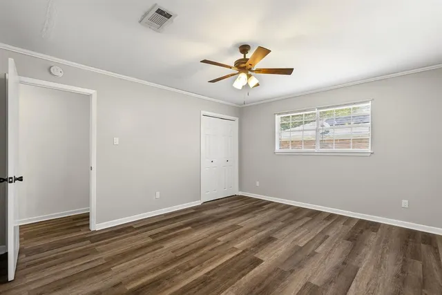 a view of empty room with wooden floor and fan