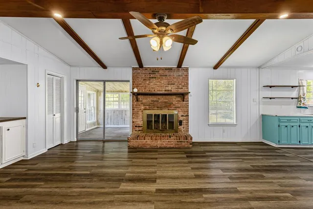 a view of a livingroom with a fireplace a chandelier and wooden floor
