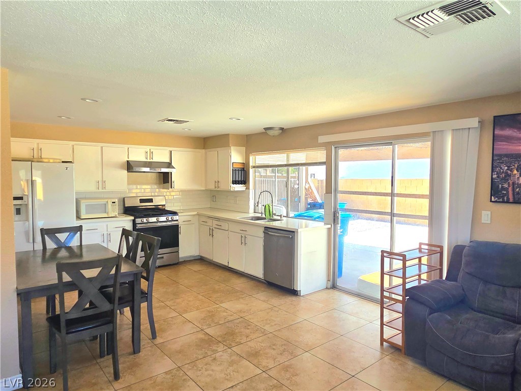 3648 Bronco Road Las Vegas, NV 89103 - Photo 2 of 24 A well-lit kitchen with sleek white cabinetry offers convenient access to the outdoor living space.