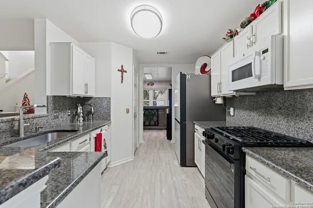 a kitchen with stainless steel appliances granite countertop a sink stove and refrigerator