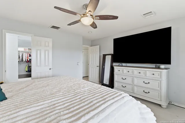 a bedroom with a bed a flat screen tv and a chandelier