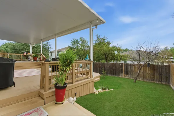 a backyard of a house with table and chairs potted plants and large tree