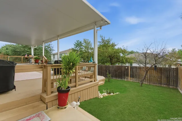 a backyard of a house with table and chairs potted plants and large tree