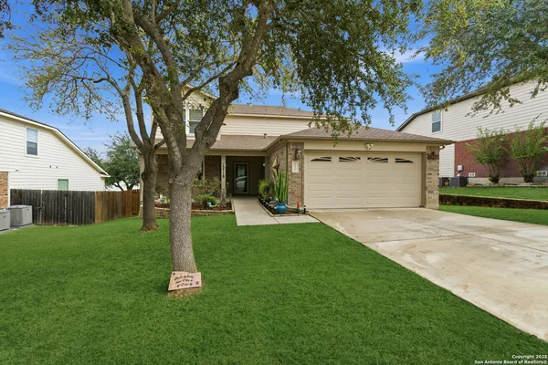 a front view of a house with a yard and tree