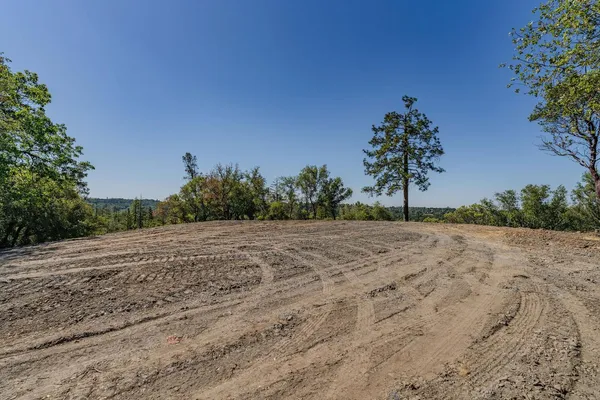 a view of dirt field with trees in the background