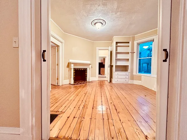 a view of empty room with wooden floor and fireplace