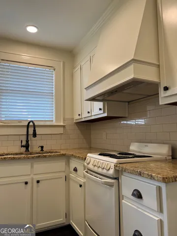 a kitchen with granite countertop white cabinets and white appliances