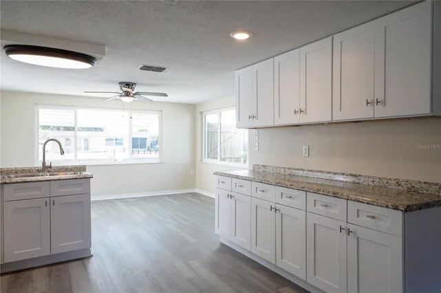 a kitchen with granite countertop white cabinets and a large window