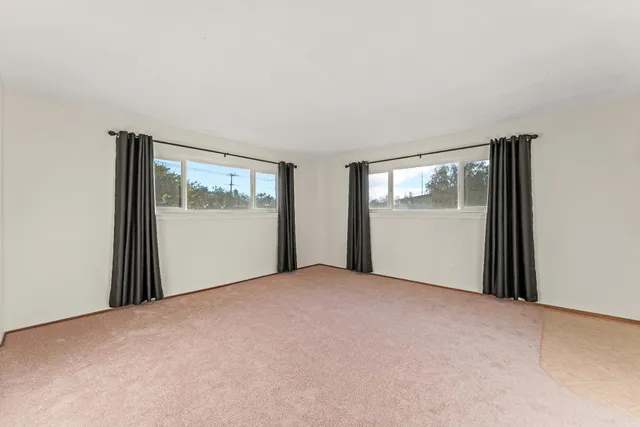 a view of an empty room with window and closet area