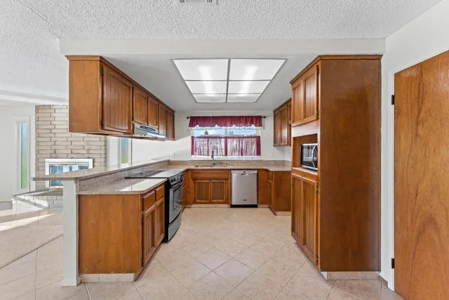 a kitchen with stainless steel appliances granite countertop a stove a sink and a microwave