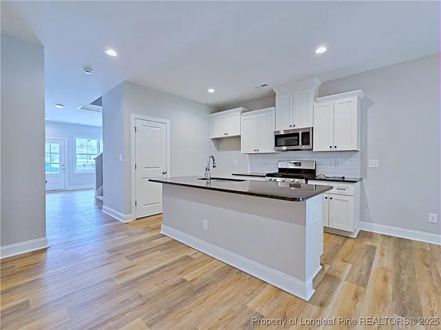 a kitchen with granite countertop a stove top oven and white cabinets