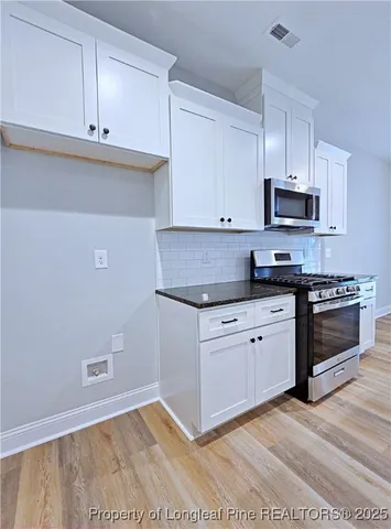 a large kitchen with granite countertop a sink and dishwasher a stove with wooden floor