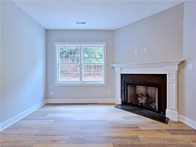 a view of empty room with wooden floor fireplace and fan