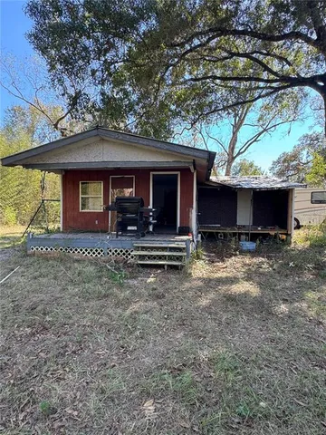 a view of house with yard and a large tree