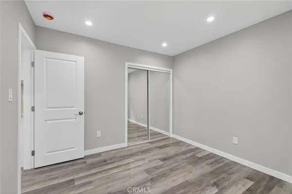 a view of an empty room with wooden floor and a ceiling fan