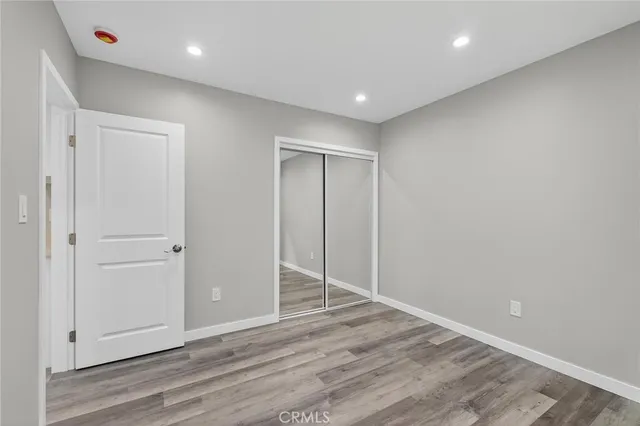 a view of an empty room with wooden floor and a ceiling fan