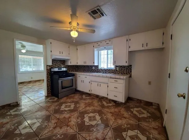 a kitchen with granite countertop a stove sink and cabinets