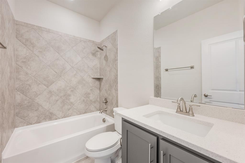 4410 Biscayne Drive Midlothian, TX 76065 - Photo 33 of 40 a bathroom with a granite countertop sink a toilet a mirror a bathtub and shower