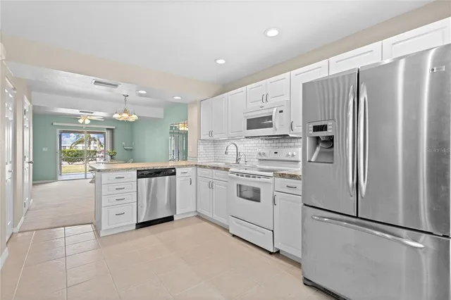 a kitchen with white cabinets stainless steel appliances and a refrigerator