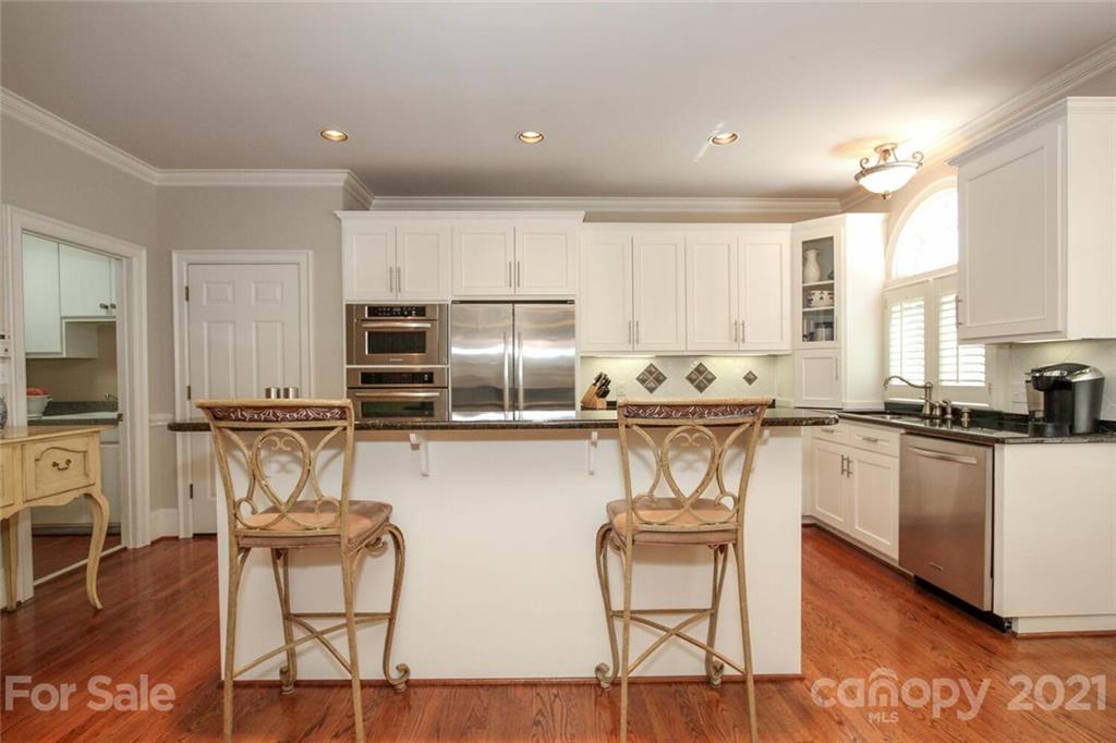 2125 South Wendover Road Charlotte, NC 28211 - Photo 15 of 48 a kitchen with stainless steel appliances granite countertop a stove top oven a sink a refrigerator with white cabinets and wooden floor
