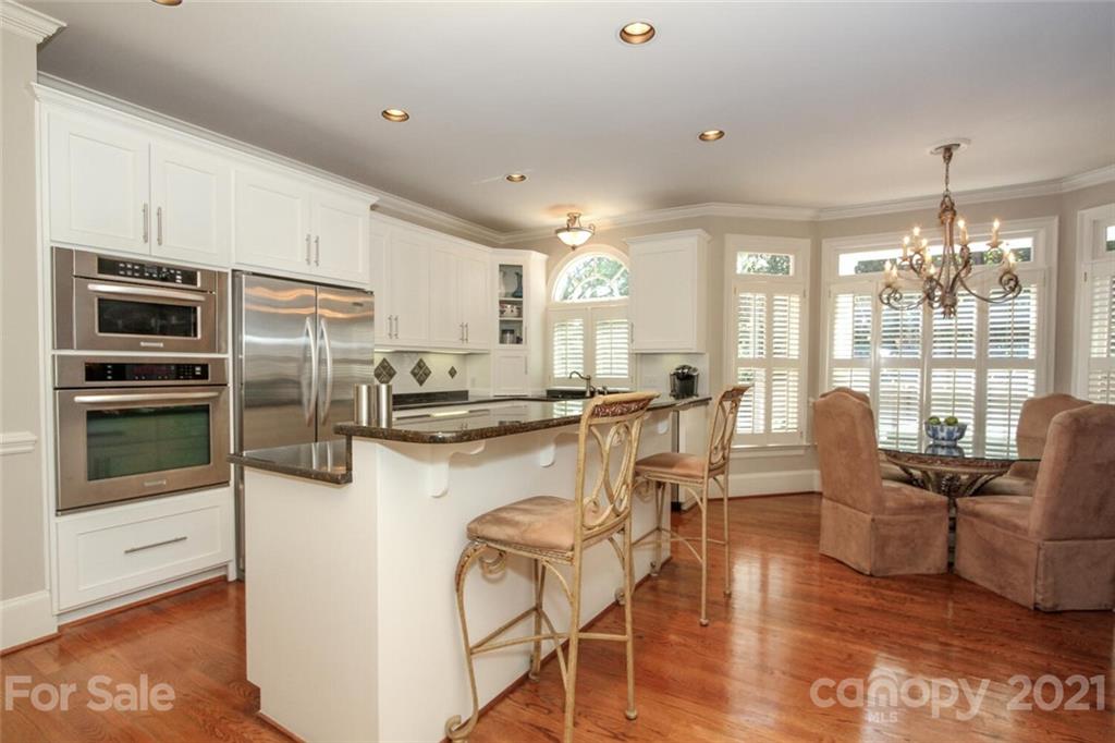 2125 South Wendover Road Charlotte, NC 28211 - Photo 16 of 48 a kitchen with stainless steel appliances granite countertop a refrigerator a stove top oven a dining table and chairs with wooden floor