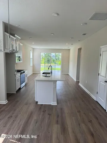 a kitchen with stainless steel appliances granite countertop a refrigerator a stove top oven a sink dishwasher and wooden floor