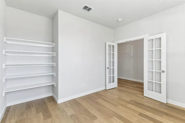 a view of an empty room with wooden floor and closet