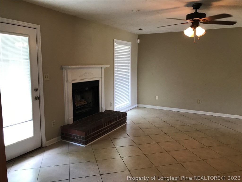 713 Rim Road Fayetteville, NC 28314 - Photo 5 of 16 a living room with a fireplace furniture a ceiling fan and a window