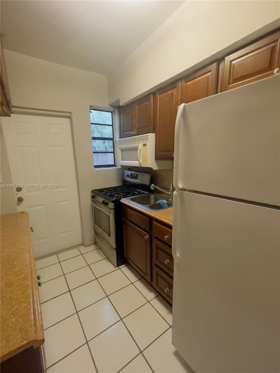 807 86th Street, Unit 805 Miami Beach, FL 33141 - Photo 6 of 10 a kitchen with a refrigerator and a stove top oven