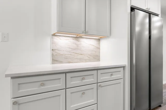 a view of a kitchen with white cabinets and a window