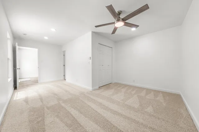 an empty room with ceiling fan and window