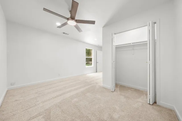 an empty room with a ceiling fan and a window
