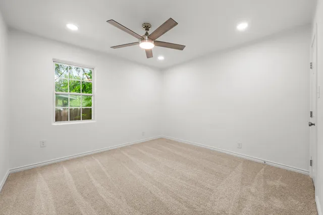 an empty room with a window and a fan