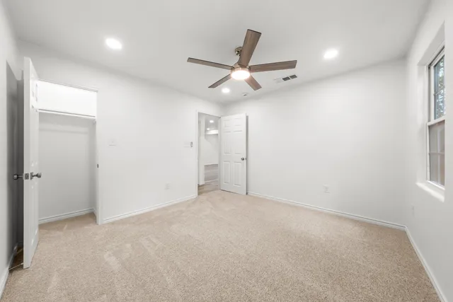 an empty room with ceiling fan and window