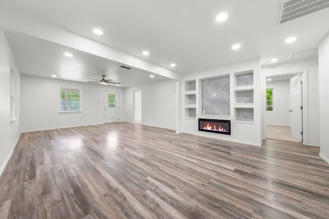 a view of an empty room with wooden floor and a window