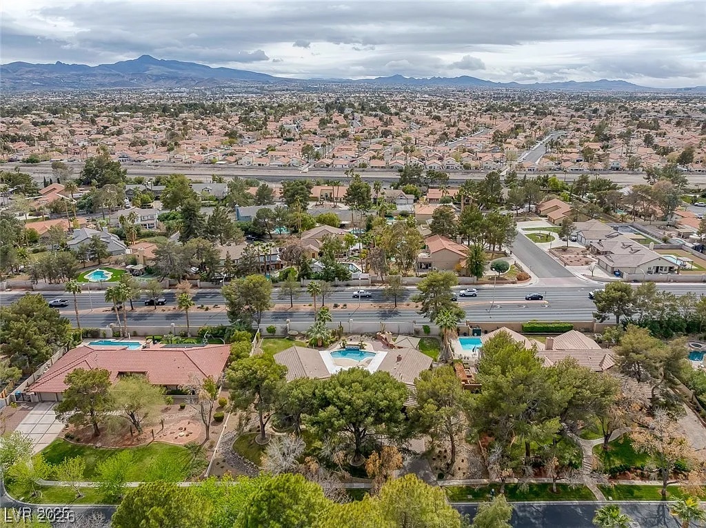 9 Quail Run Road Henderson, NV 89014 - Photo 47 of 57 An aerial perspective reveals a desert neighborhood with individual pools, mature trees, and distant mountain views.