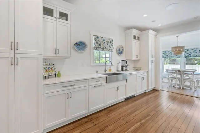 a large white kitchen with white cabinets and wooden floor