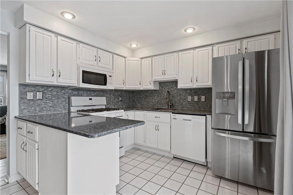 10 Rolling Road Cranberry Township, PA 16066 - Photo 5 of 39 Wow! Delight in this exceptional eat-in kitchen boasting quartz countertops, a stylish tiled backsplash, ample white cabinets, recessed lighting, a new stainless upscale refrigerator, and included gas stove, microwave, & dishwasher! The white tiled floors beautifully accent the white cabinetry and neutral quartz counters.