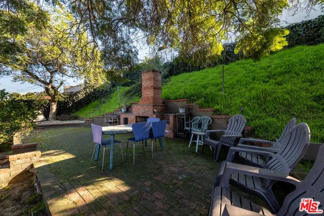 a view of a patio with table and chairs potted plants and large tree