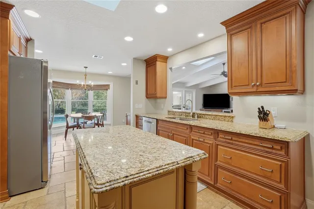 a kitchen with stainless steel appliances granite countertop a dining table chairs and refrigerator