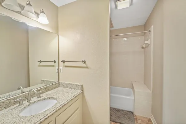 a bathroom with a granite countertop sink a mirror and shower
