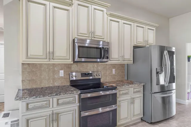 a kitchen with stainless steel appliances granite countertop a stove a refrigerator and a microwave