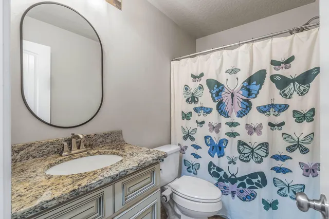 a bathroom with a granite countertop sink a toilet and a mirror