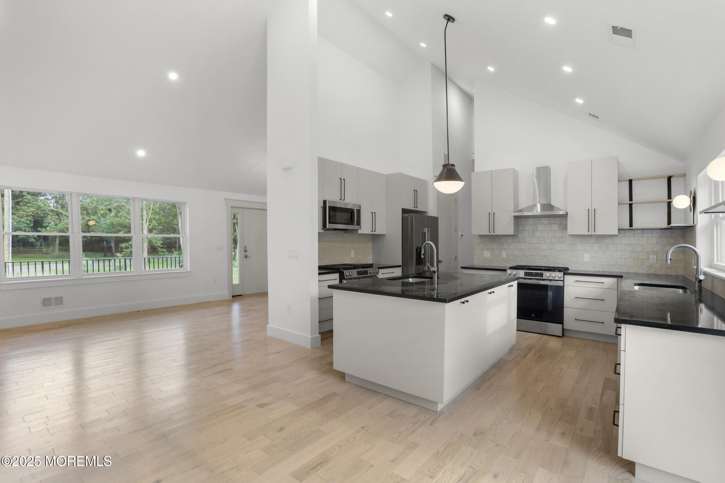 a large kitchen with stainless steel appliances kitchen island a large counter top a sink a stove and a refrigerator