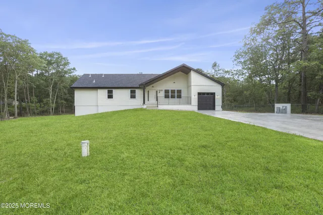 a view of house with a big yard and large trees