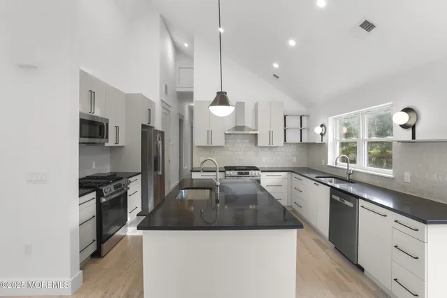 a kitchen with stainless steel appliances granite countertop a sink a stove and a refrigerator