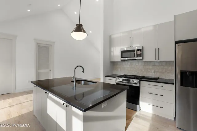 a kitchen with kitchen island a sink stainless steel appliances and cabinets