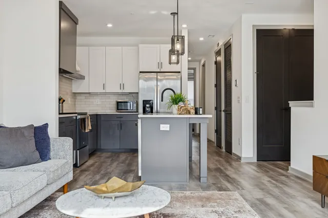 a living room with stainless steel appliances kitchen island granite countertop furniture and a fireplace